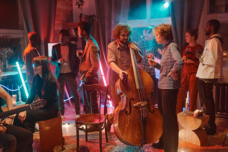 Group of young people drinking alcohol drinks listening to music and talking during social event